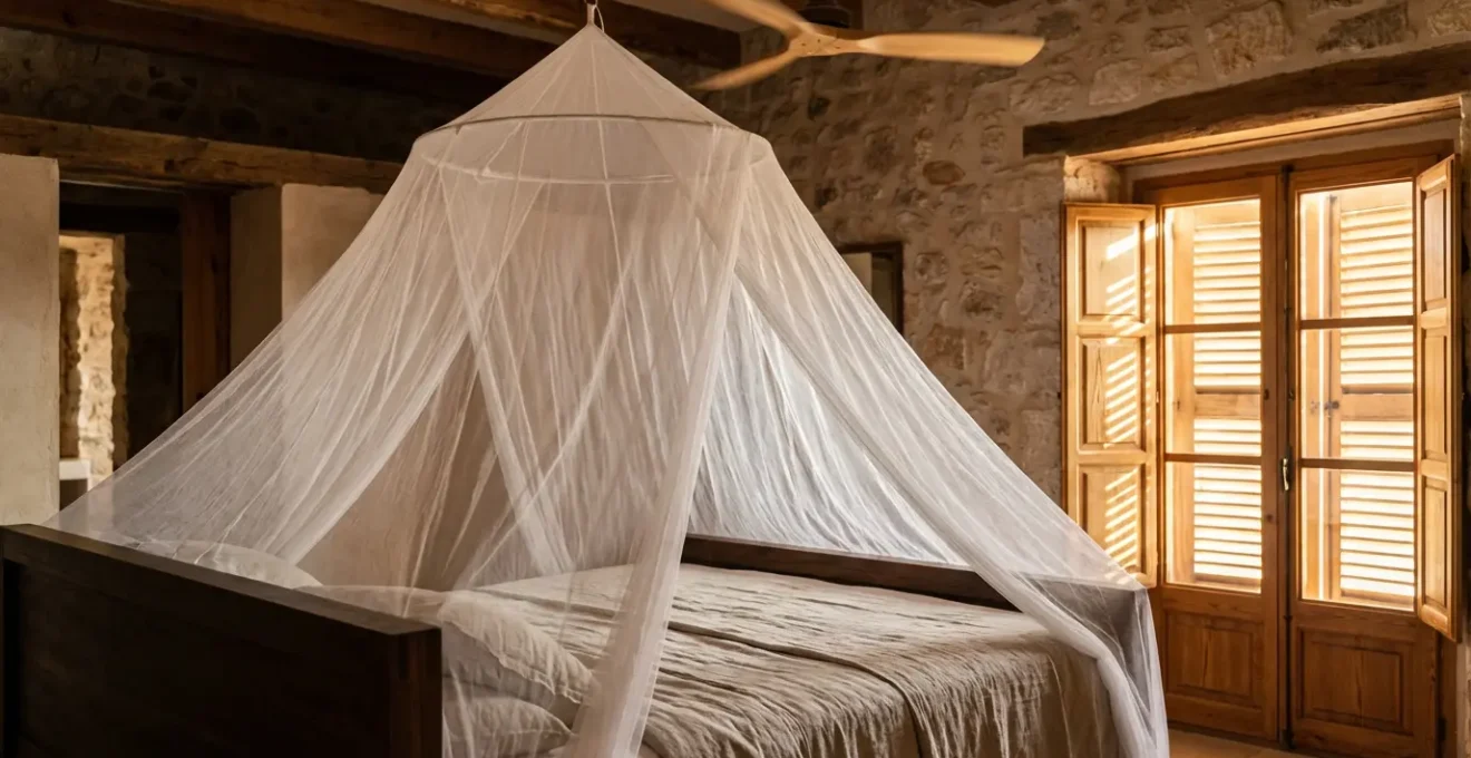 Intérieur de chambre camarguaise avec moustiquaire de lit, ventilateur et volets fermés créant une protection naturelle